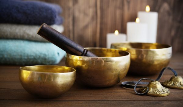 Tibetan handcrafted singing bowls with towels and candles on wooden background